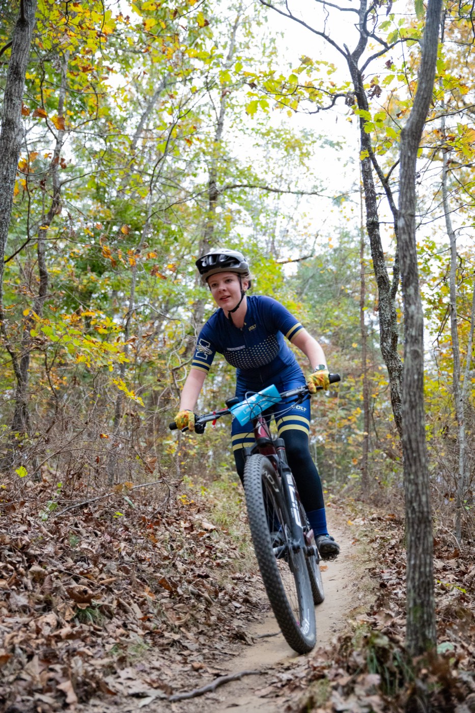 Rider descending an autumn singletrack trail on race day