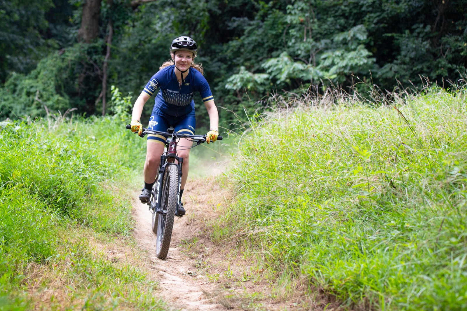 Rider smiling down a grassy summer singletrack