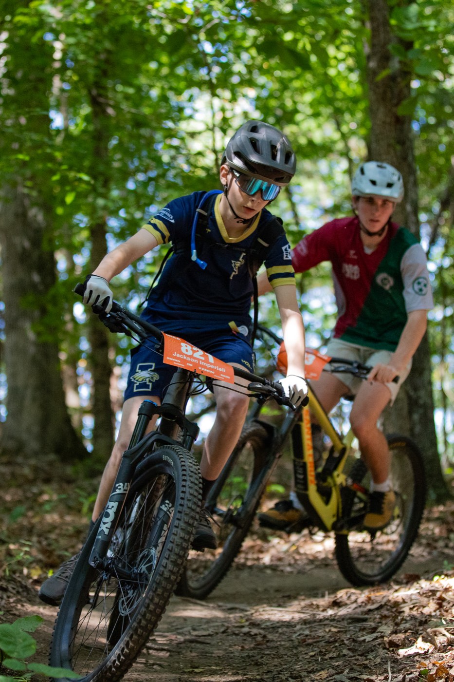 Rider leading a friend down wooded singletrack